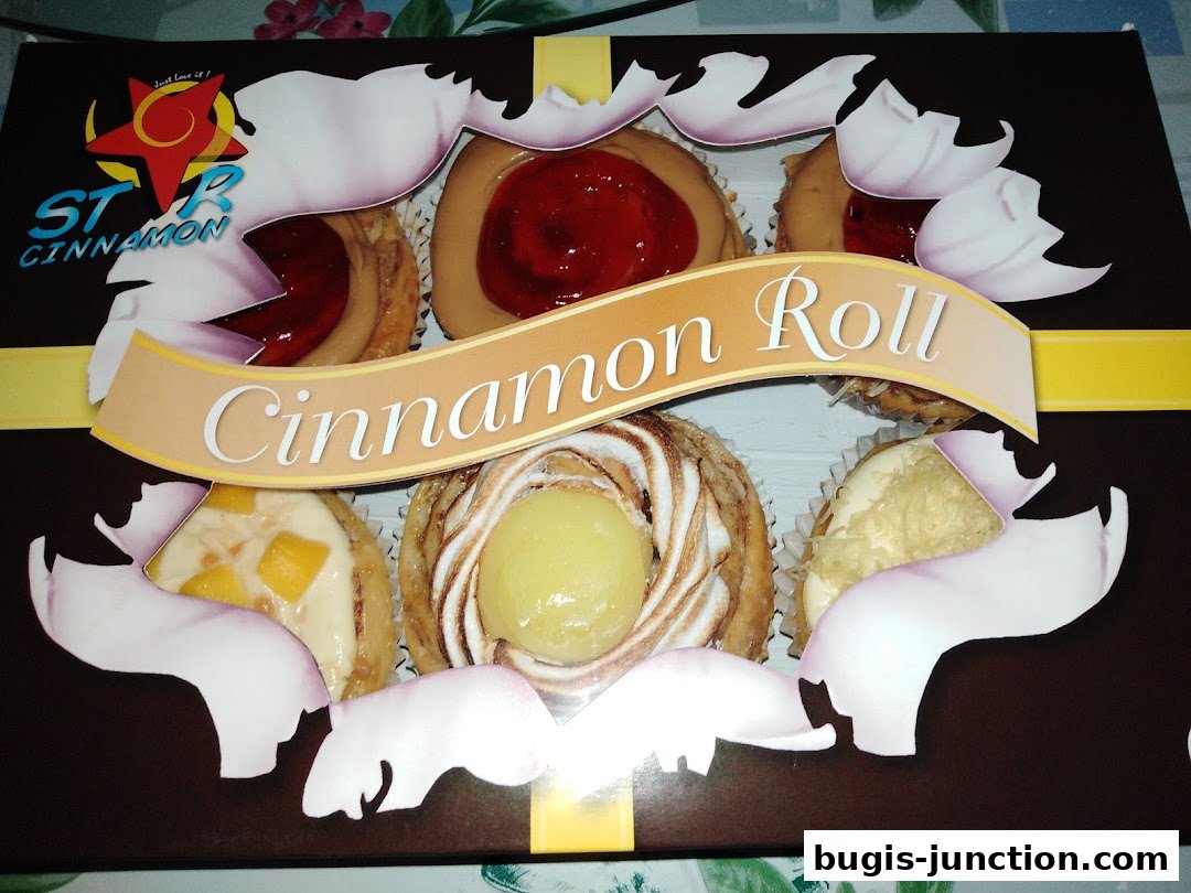 A box of assorted cinnamon rolls with various toppings and fillings.