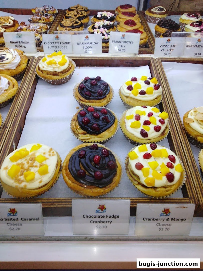 A display of various sweet pastries and buns with labels and prices.