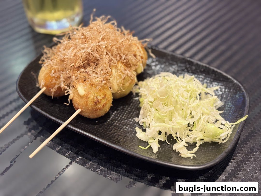 A plate of takoyaki topped with bonito flakes and a side of shredded cabbage.