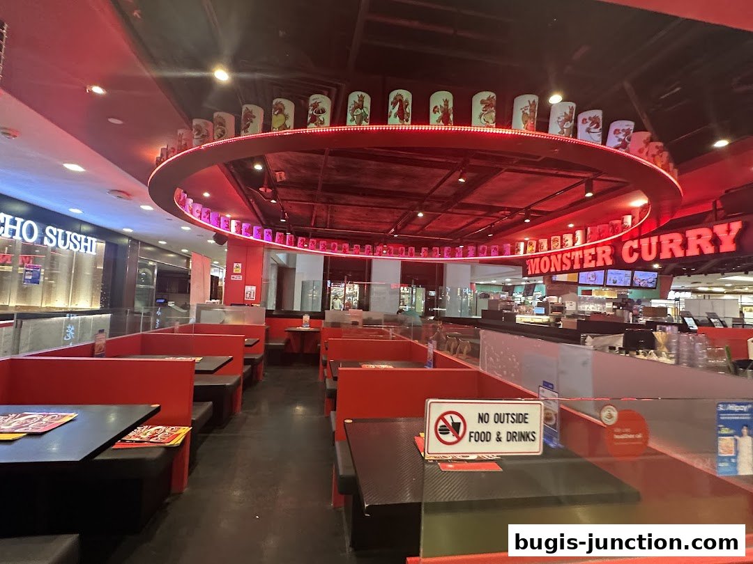 Interior of Monster Curry restaurant with red booth seating and a prominent sign.
