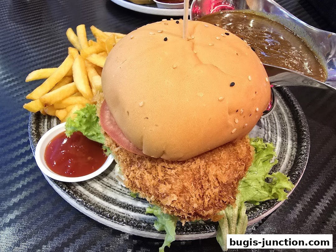 A delicious-looking curry burger with fries and a side of ketchup and curry sauce.