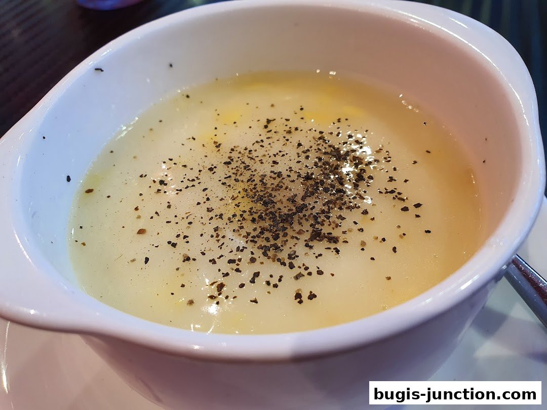 A close-up shot of a creamy soup topped with freshly ground black pepper.