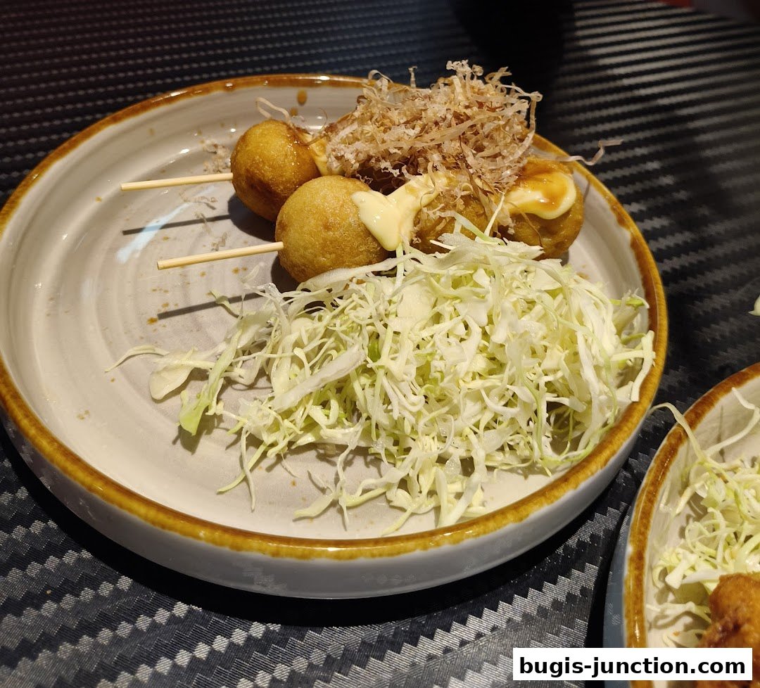 A plate of takoyaki with shredded cabbage and bonito flakes, drizzled with sauce.