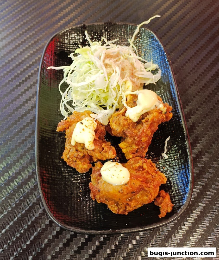 Crispy fried chicken pieces topped with mayonnaise and served with a side of shredded cabbage salad.