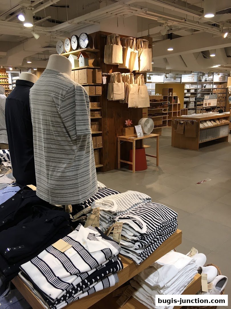 Interior view of a MUJI store showcasing folded apparel and display shelves.