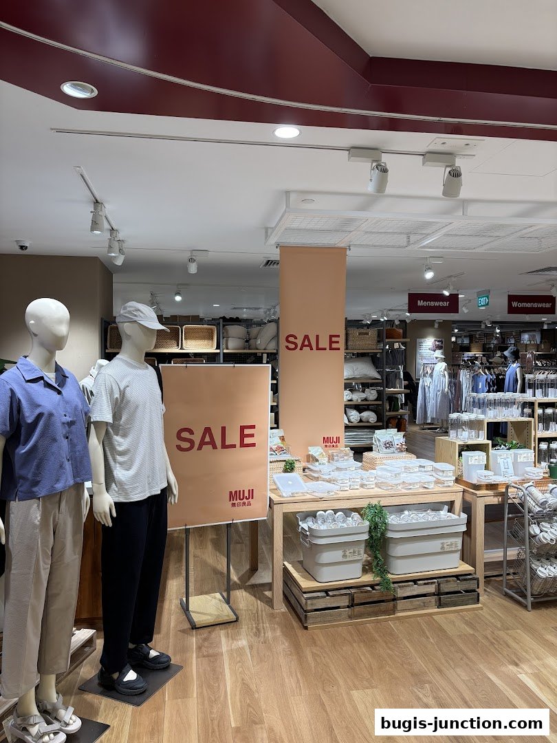Mannequins display clothing next to a large 'SALE' banner in a MUJI store.