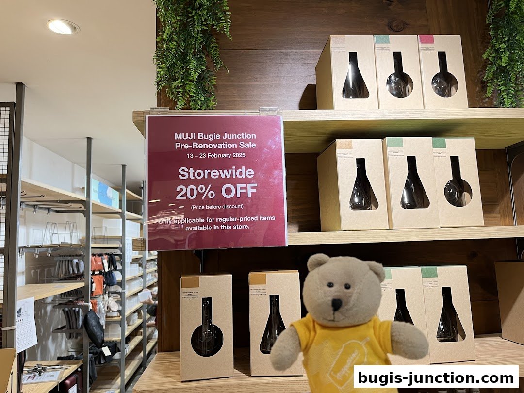 A sign announces a storewide 20% off sale at MUJI Bugis Junction, with products on shelves.