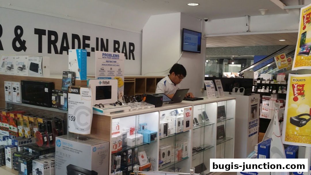 A retail store interior with electronics and a staff member working at a counter.