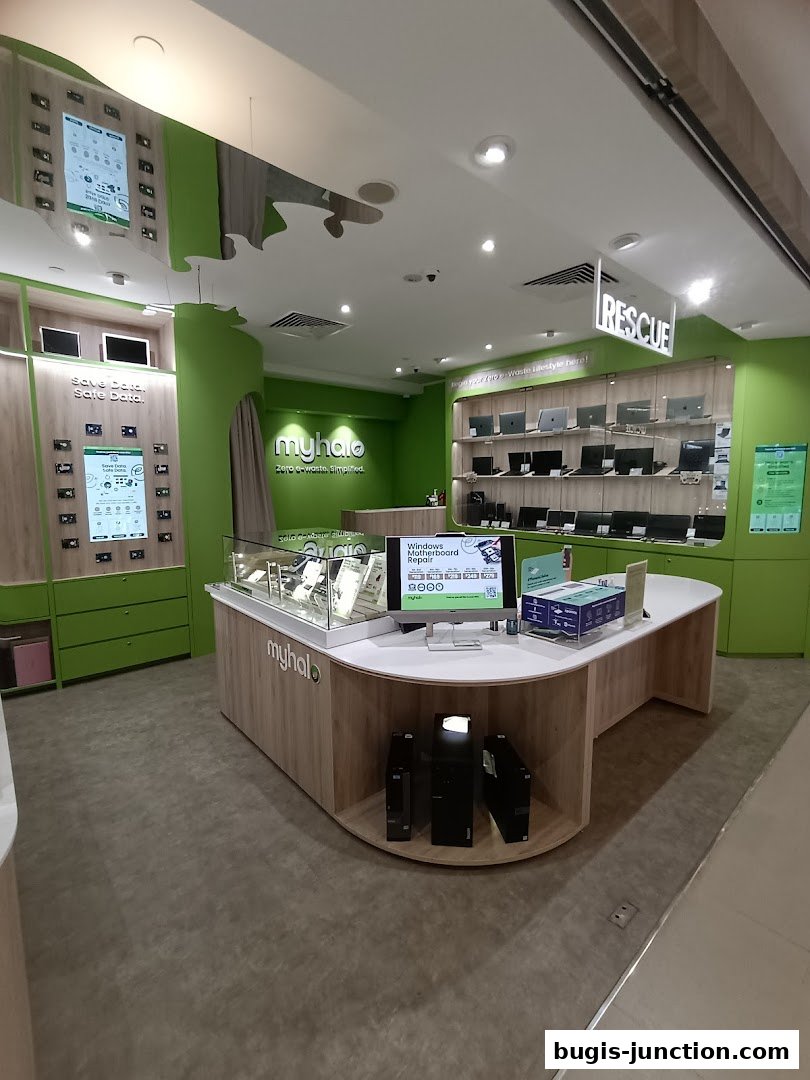 Interior view of a brightly lit electronics store with laptops displayed and a counter.