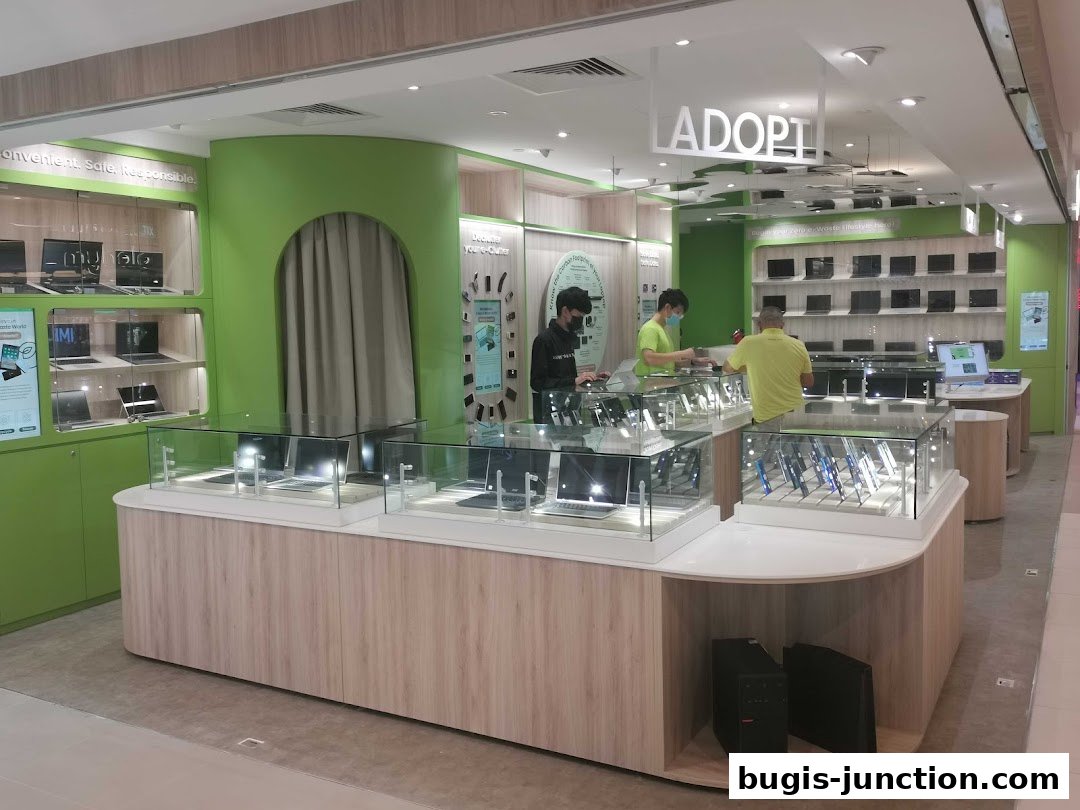 Interior view of a modern electronics store showcasing laptops and accessories with staff assisting customers.