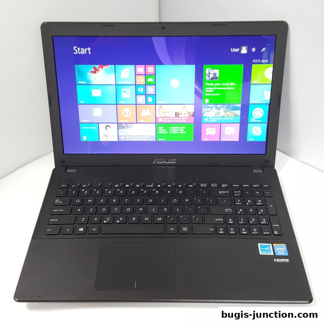 A black ASUS laptop is displayed open, showing the Windows 8 start screen and keyboard.