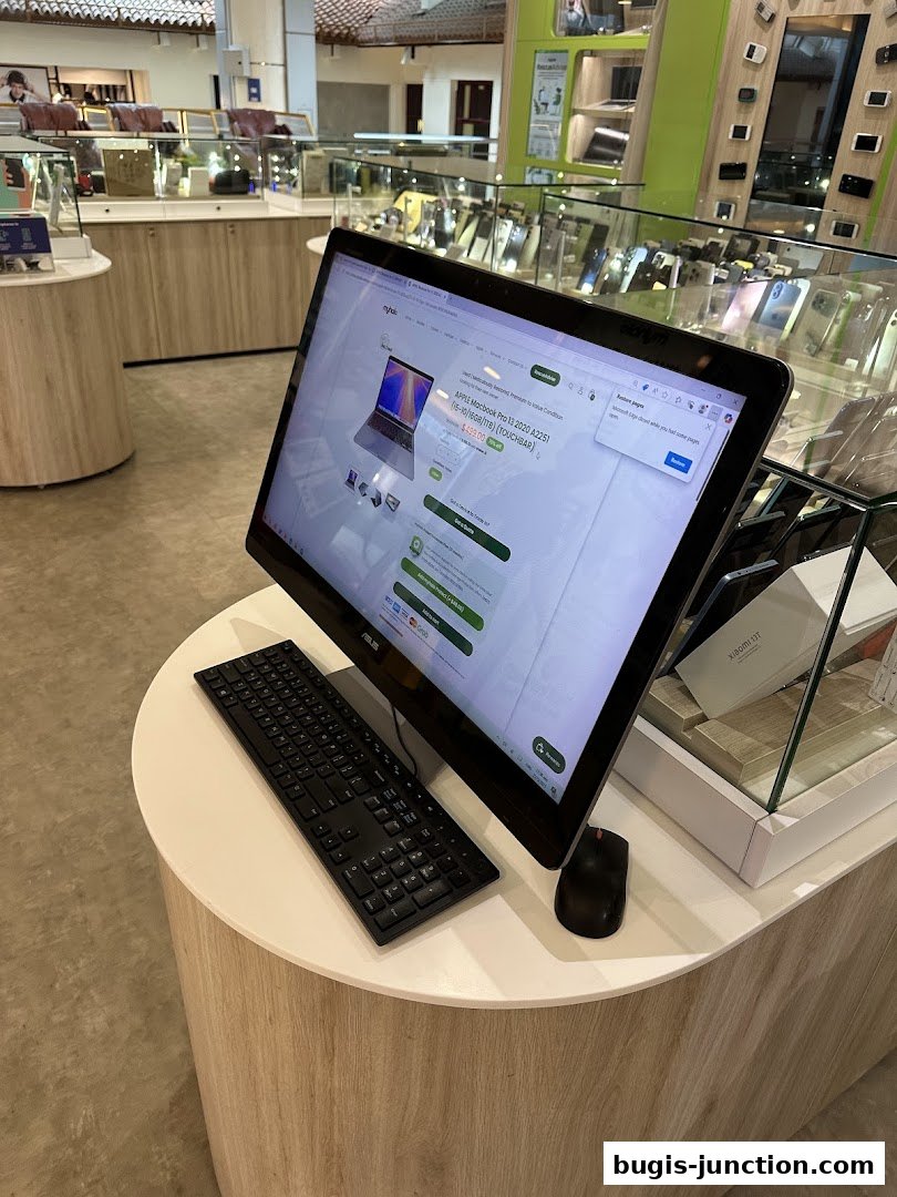 A computer displaying a laptop for sale at a retail store with other electronics in the background.