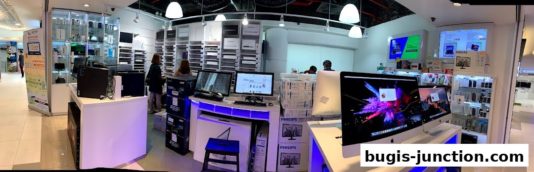 Interior view of a modern electronics store showcasing Apple computers and accessories.