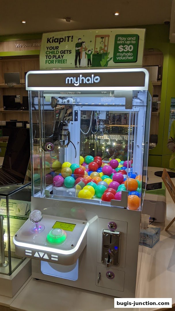 A claw machine filled with colorful balls, branded 'myhalo', with a promotional sign.