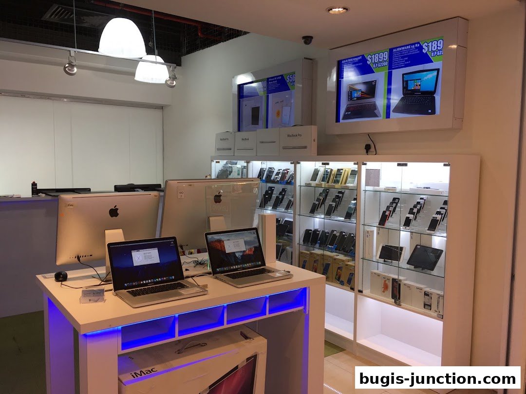 Interior of a tech store showcasing Apple computers and various electronic devices in display cases.
