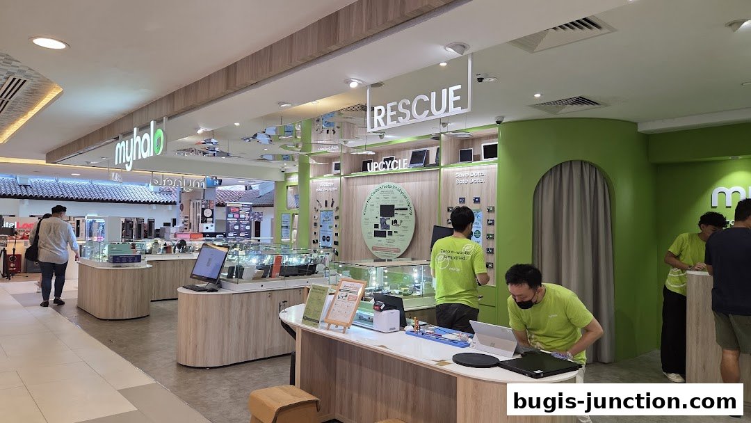 Interior view of a brightly lit electronics store with displays of laptops and accessories.