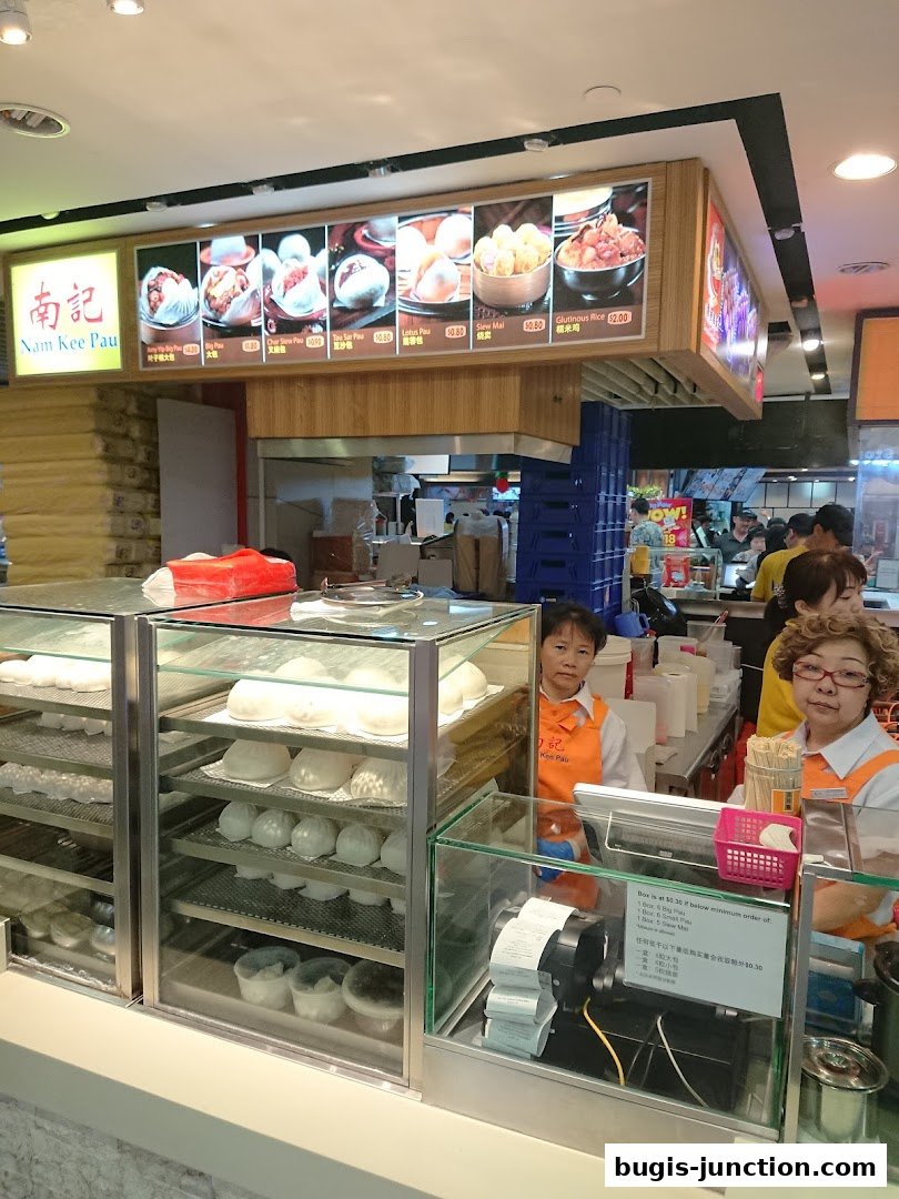 Nam Kee Pau shop interior with display cases of steamed buns and staff behind the counter.