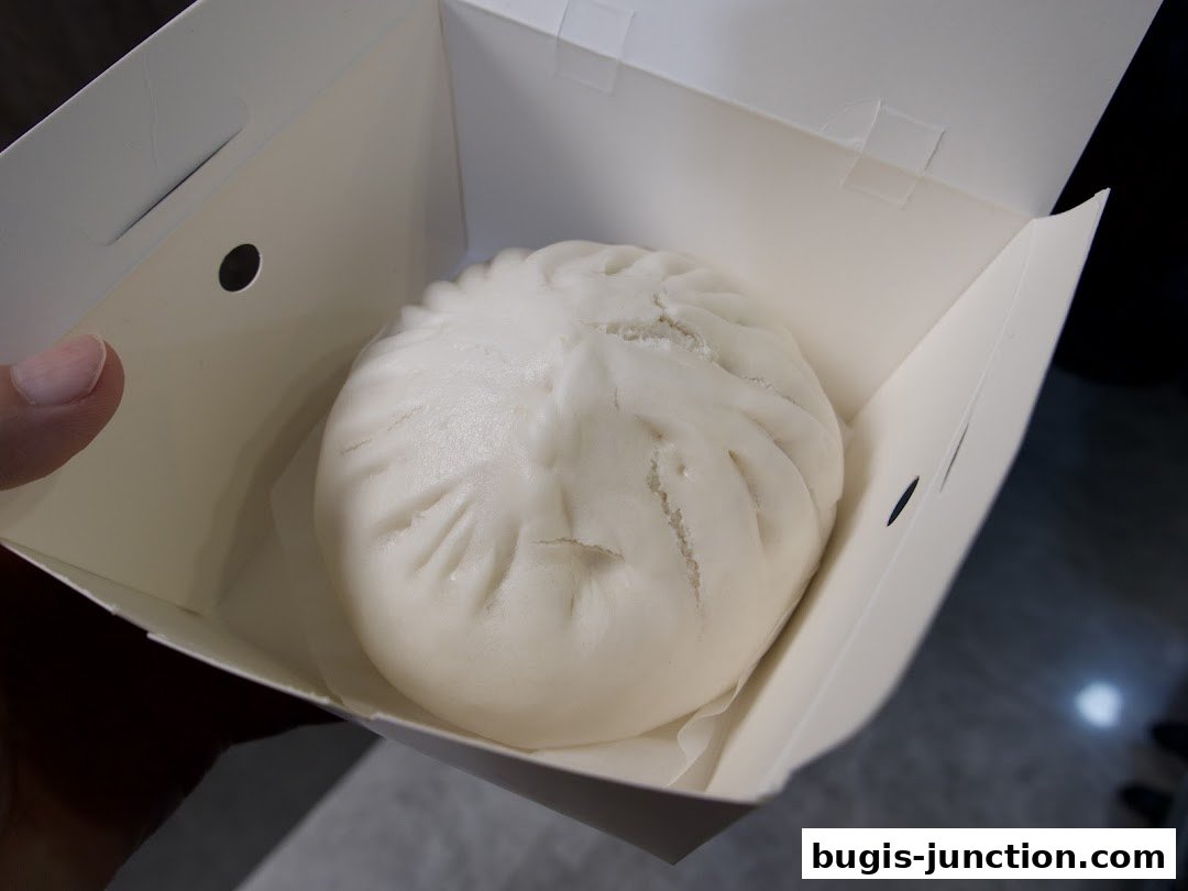 A close-up shot of a steamed bun in a white takeout box.
