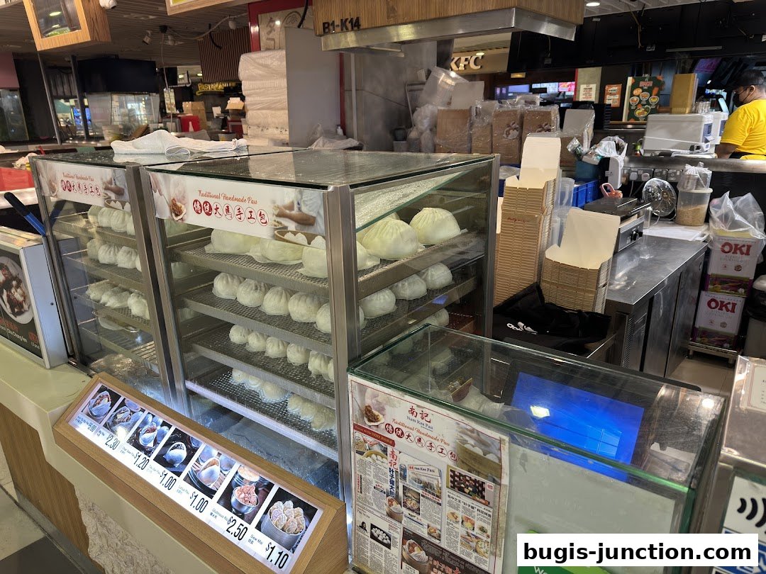 A display case filled with steamed buns and a menu board showing prices and images of food items.
