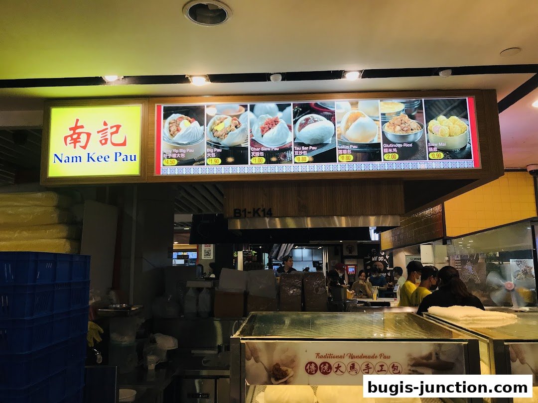 A brightly lit menu board displays various steamed buns and glutinous rice dishes from Nam Kee Pau.