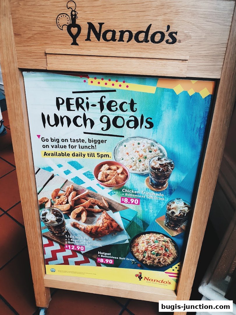 A Nando's A-frame sign advertising lunch specials with pictures of chicken and sides.
