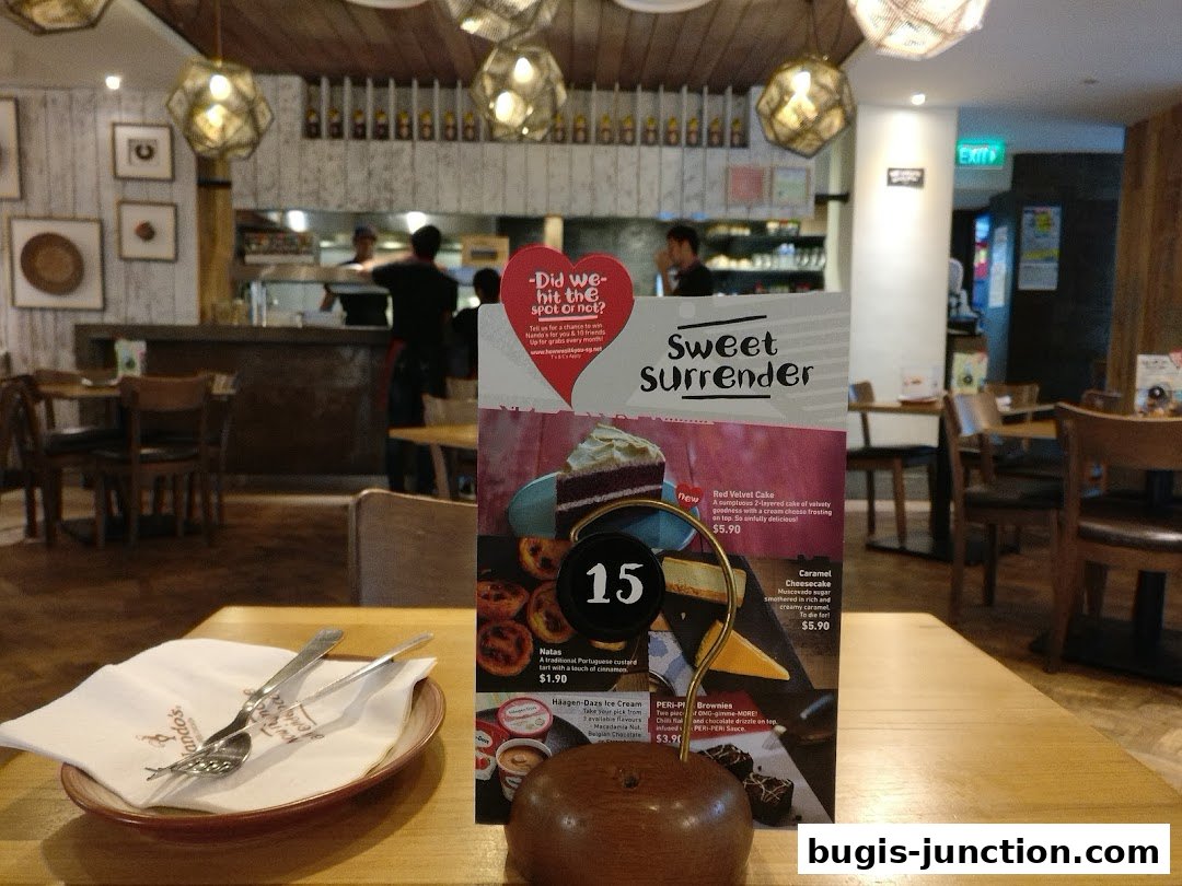A table setting at Nandos with a menu featuring desserts and a glimpse of the restaurant interior.