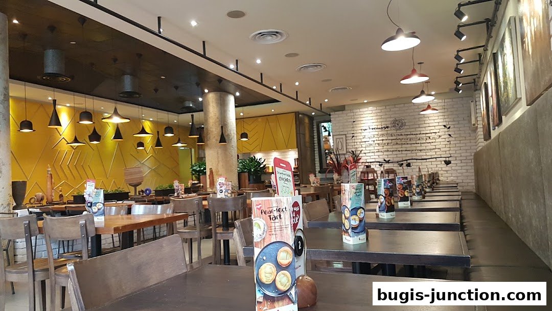 Interior view of a Nandos restaurant with tables, chairs, and decorative lighting.