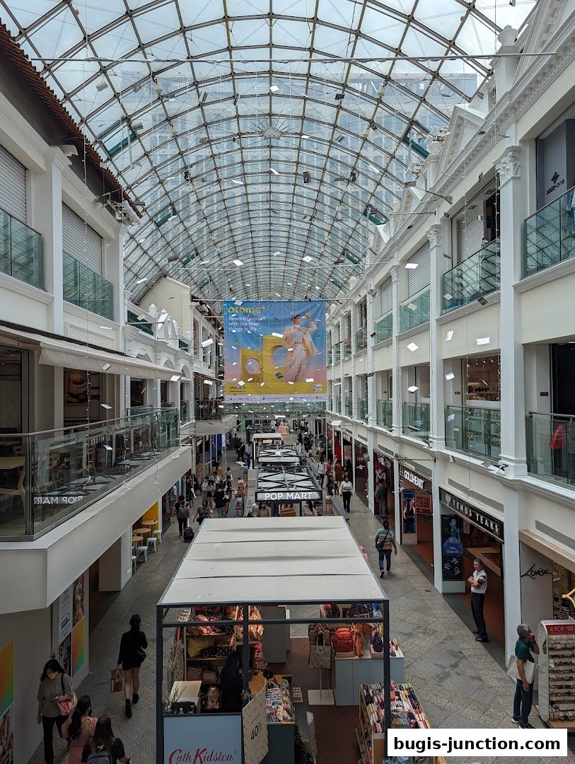 A bustling indoor shopping mall with a glass ceiling and multiple levels of shops.