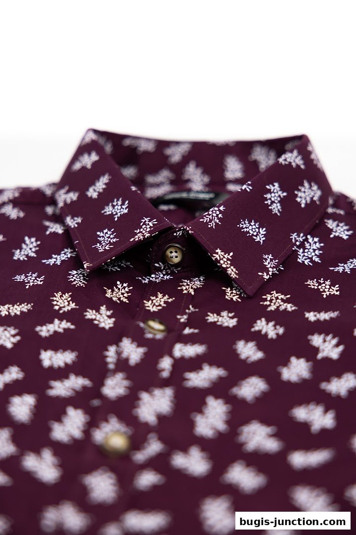 Close-up of a burgundy shirt with a white floral pattern and button details.