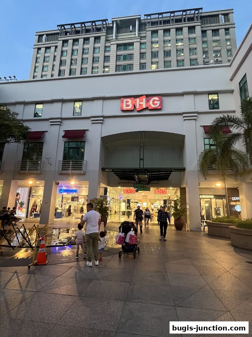 A family walks towards the entrance of a shopping mall with a prominent BHG sign.