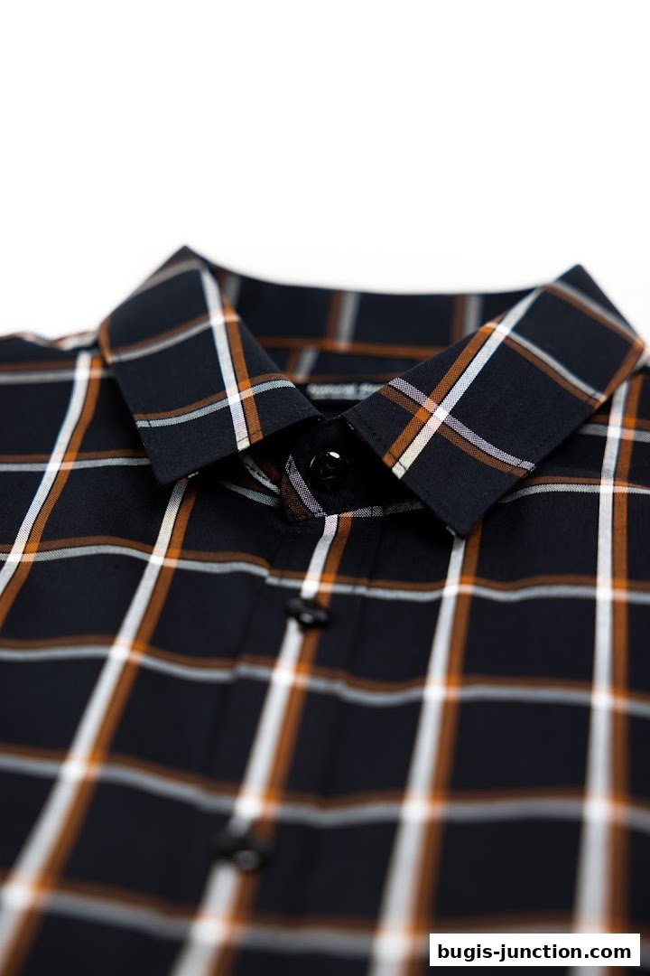 Close-up of a dark plaid shirt with orange and white lines and black buttons.