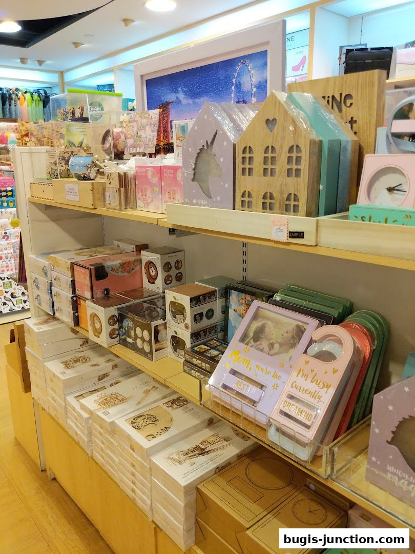 Shelves filled with various stationery, gifts, and decorative items, including wooden houses and photo frames.