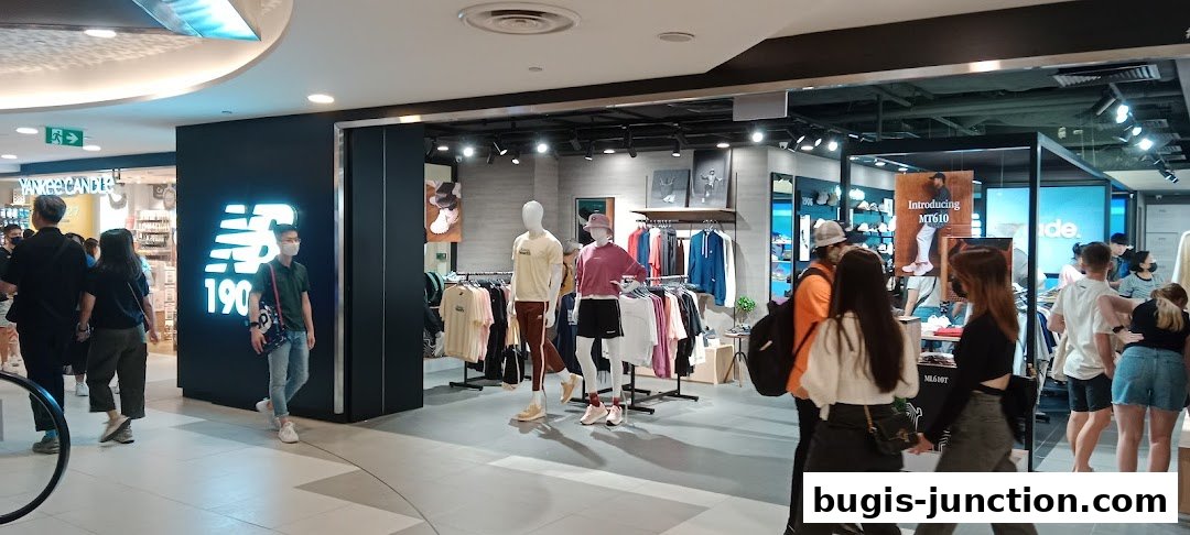 Interior view of a New Balance store with mannequins displaying apparel and shelves stocked with shoes.