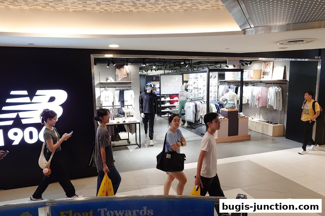 People walk past a New Balance store displaying apparel and footwear.