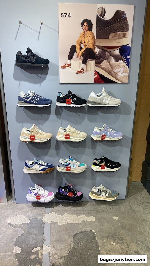 New Balance store display featuring various sneaker models and a promotional poster.