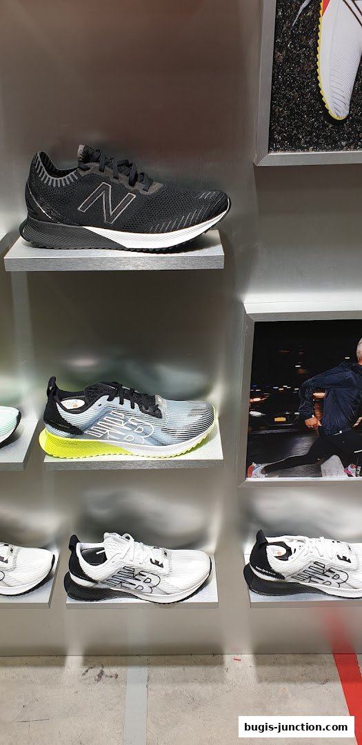 A display of New Balance running shoes on shelves, with a lifestyle image of a runner in the background.