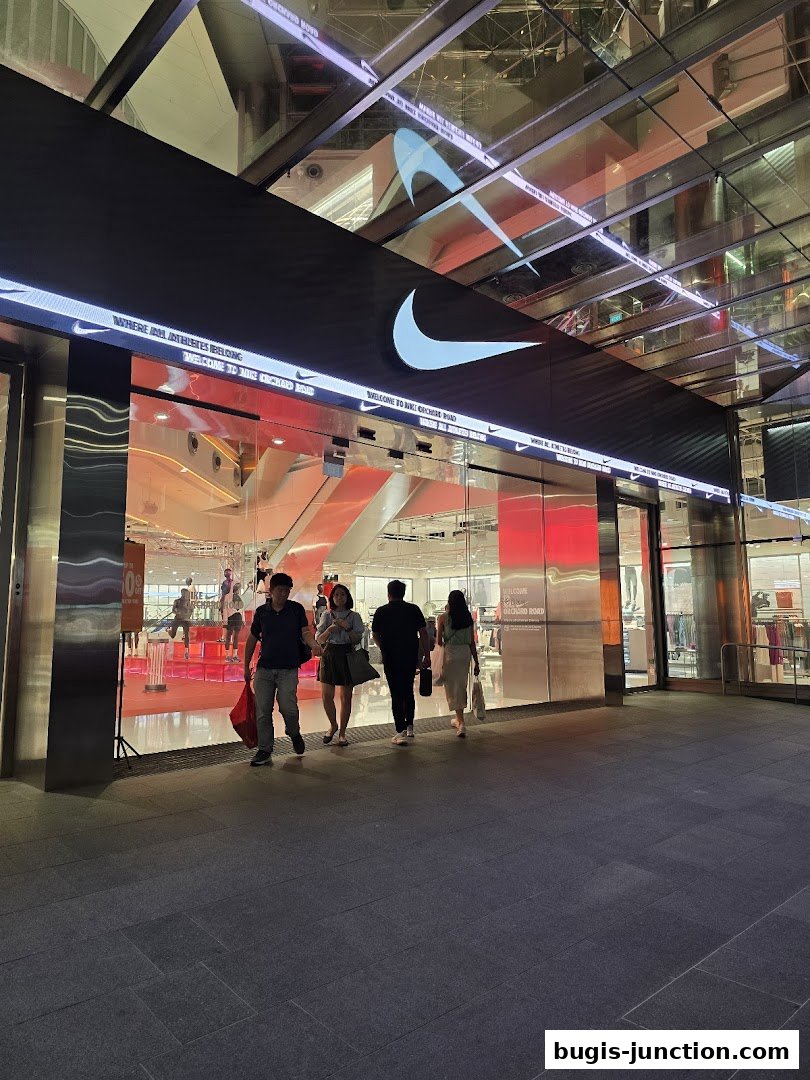 People walk towards the illuminated Nike store entrance at night, showcasing the brand's iconic logo.