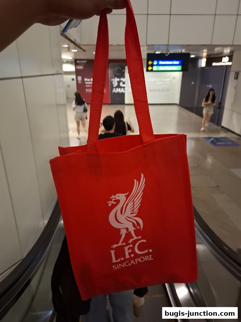 A red tote bag with the L.F.C. Singapore logo is held up.
