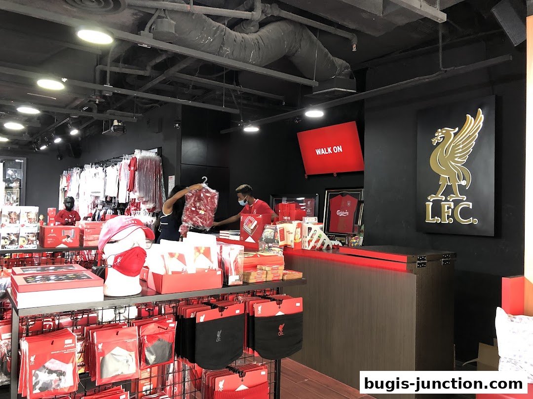 Interior of a Liverpool FC retail store with merchandise and staff.