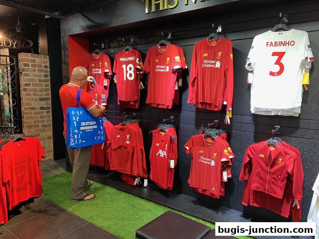 A customer browses Liverpool FC merchandise, including jerseys and jackets, displayed on a wall.