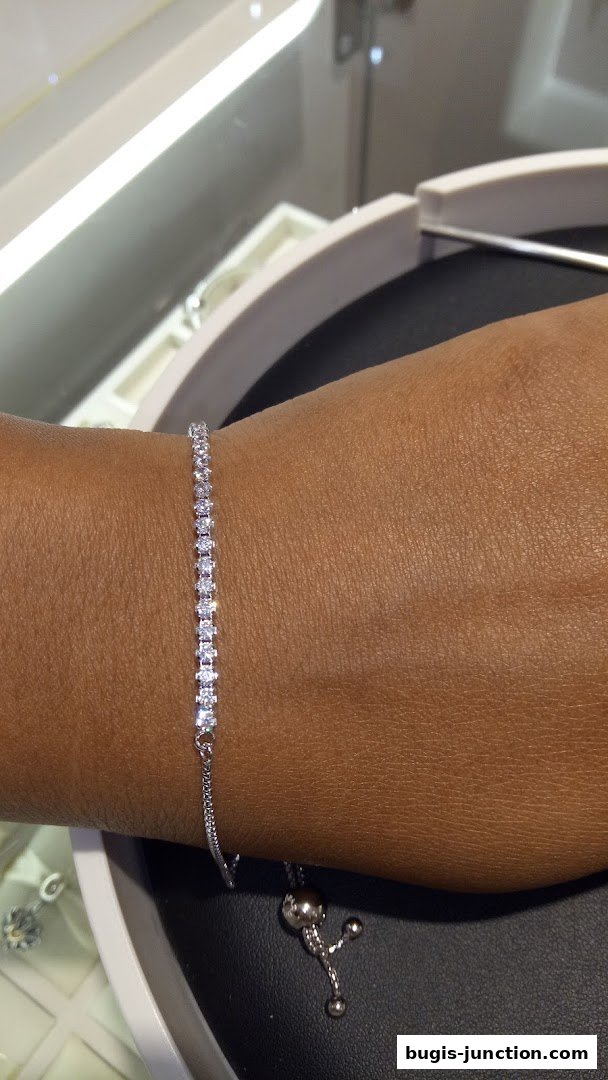 A close-up shot of a delicate diamond tennis bracelet on a person's wrist.