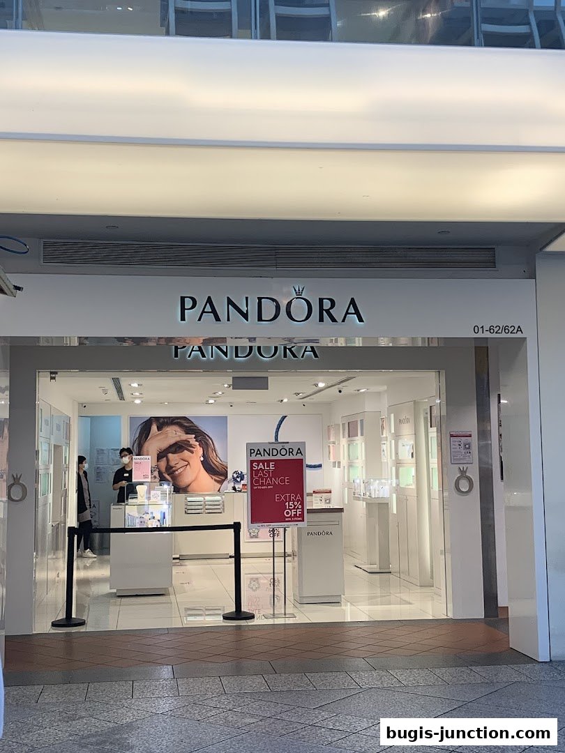 The entrance of a Pandora jewelry store with a sale sign and displays inside.