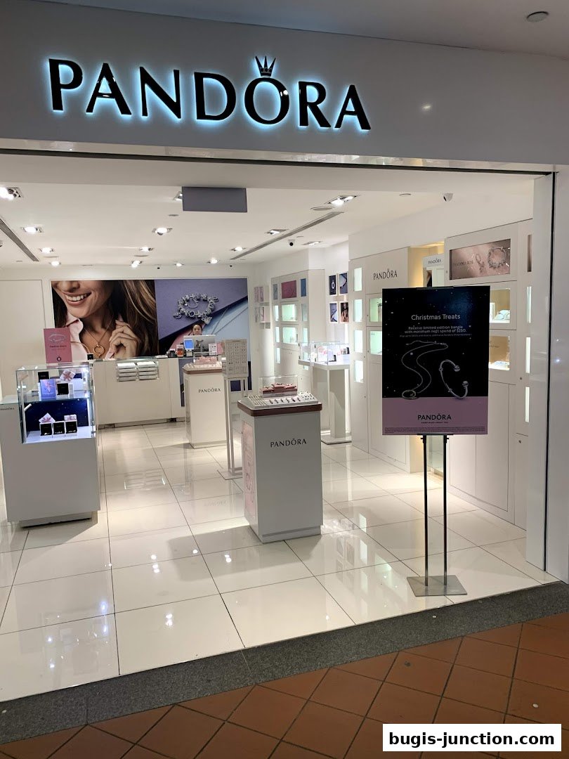 The entrance of a Pandora jewelry store with illuminated signage and displays.
