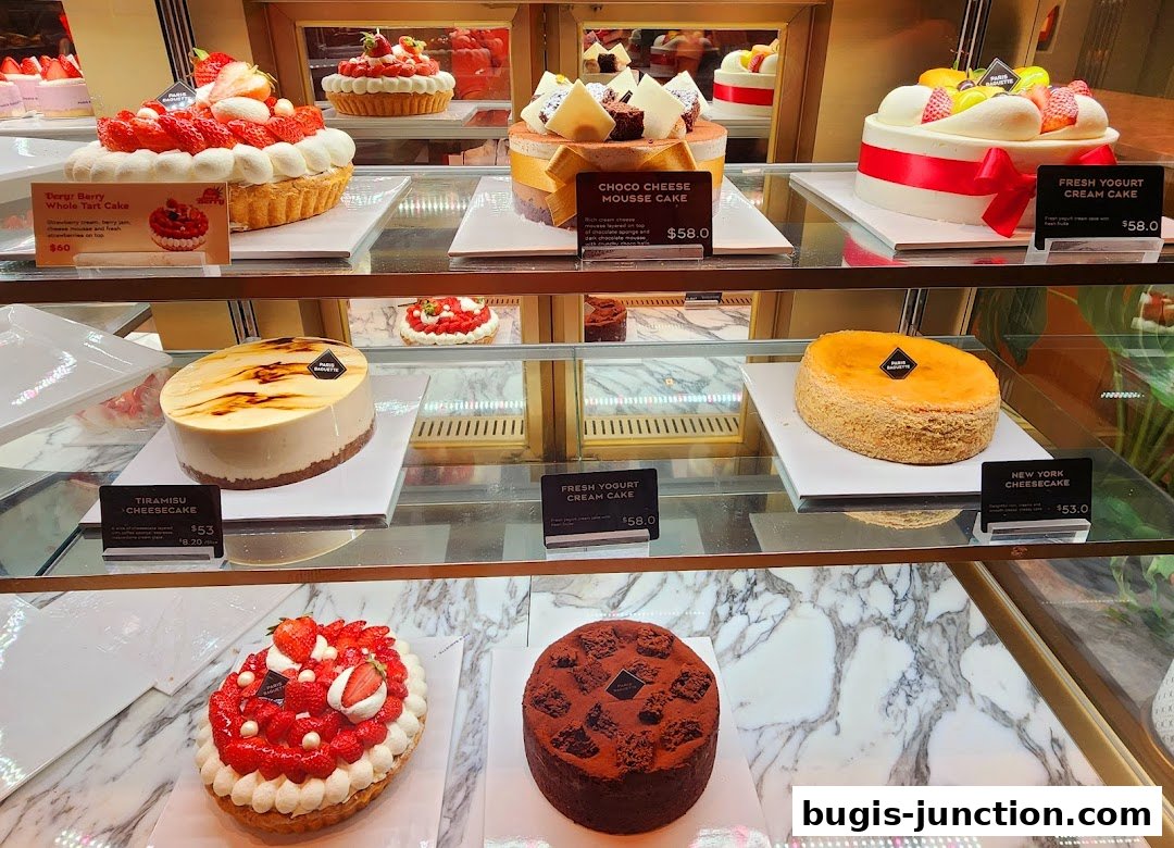 A display case filled with various beautifully decorated cakes and tarts from Paris Baguette.