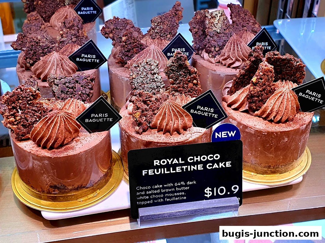 A display of decadent chocolate cakes with intricate toppings and branding.