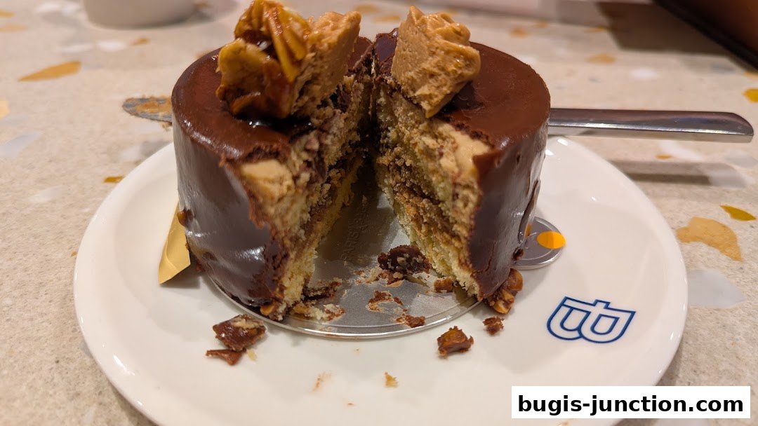 A delicious chocolate cake with caramel and nuts, cut in half on a white plate.