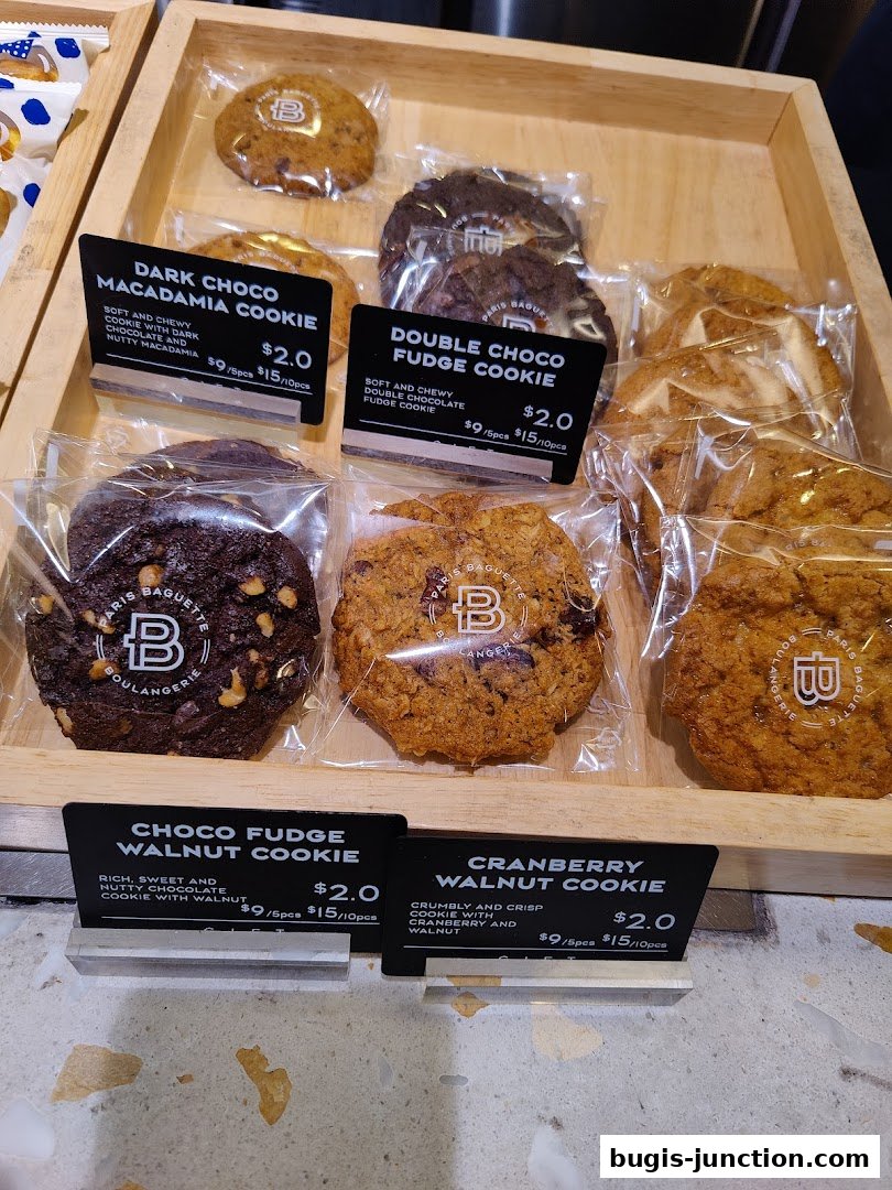 A display of freshly baked cookies from Paris Baguette, featuring various flavors and prices.