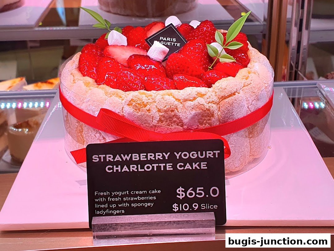 A strawberry yogurt charlotte cake with fresh strawberries and a red ribbon.