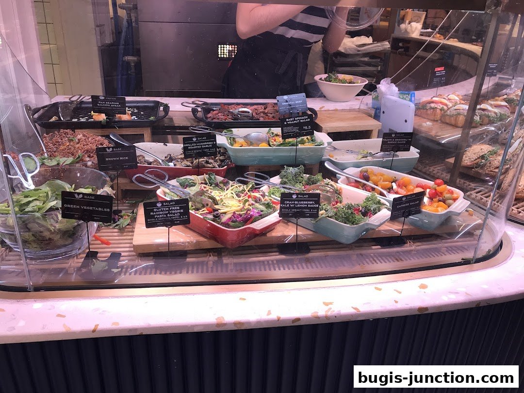 A display case filled with various salads, rice, and sandwiches at Paris Baguette.