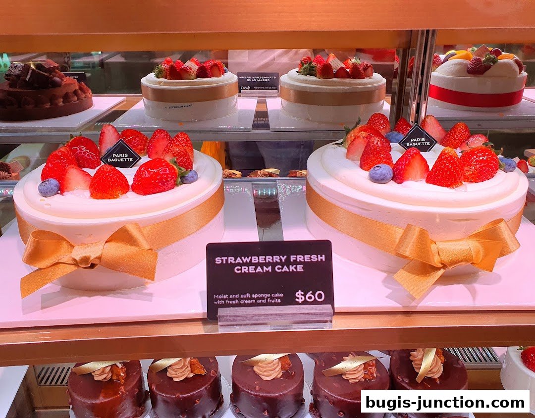 A display of beautifully decorated cakes, featuring fresh strawberries and cream.